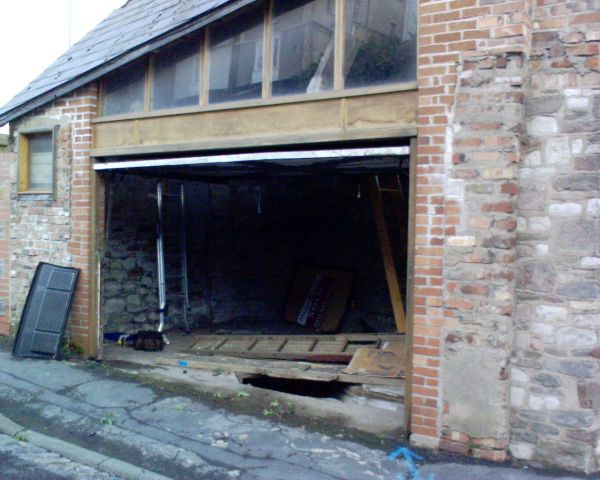 The front. With the up and over door open you can see the inspection pit and to the right, the wooden stairs/ladder going up.